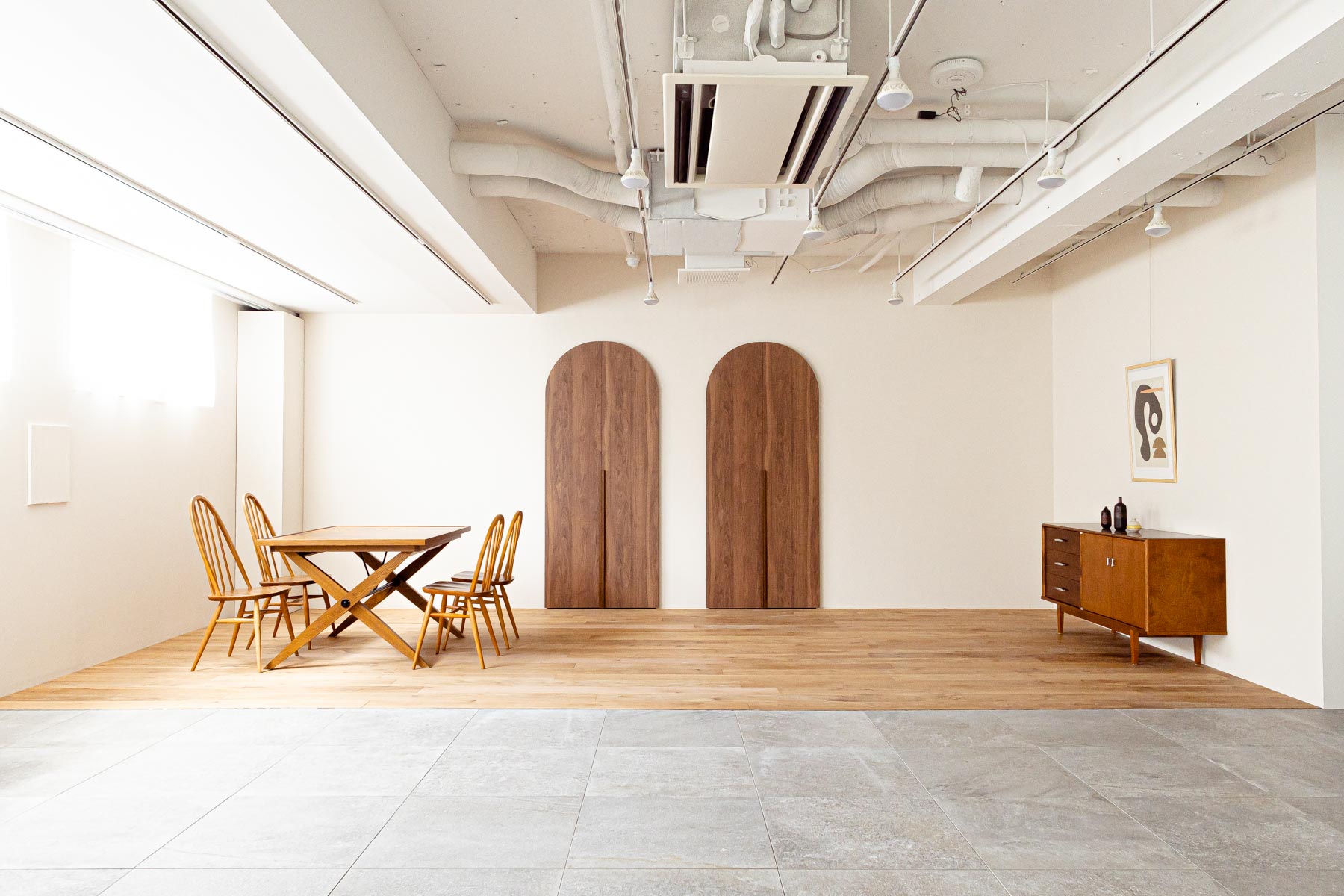 2枚の円形ドアがある部屋に、テーブルセットとチェストが配置された写真
