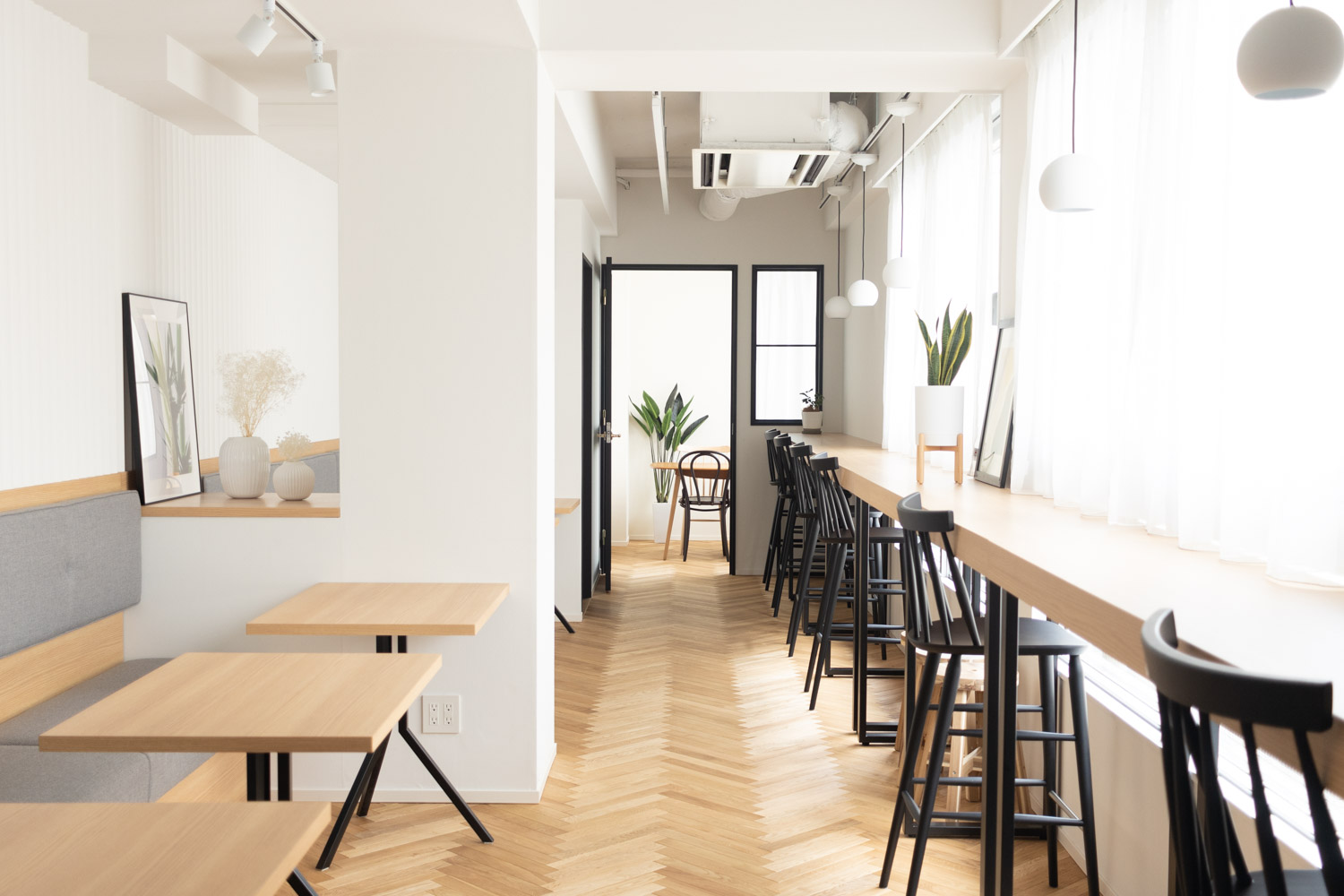 自然光で明るい窓際に、テーブル・椅子が配置されたカフェ空間のような写真