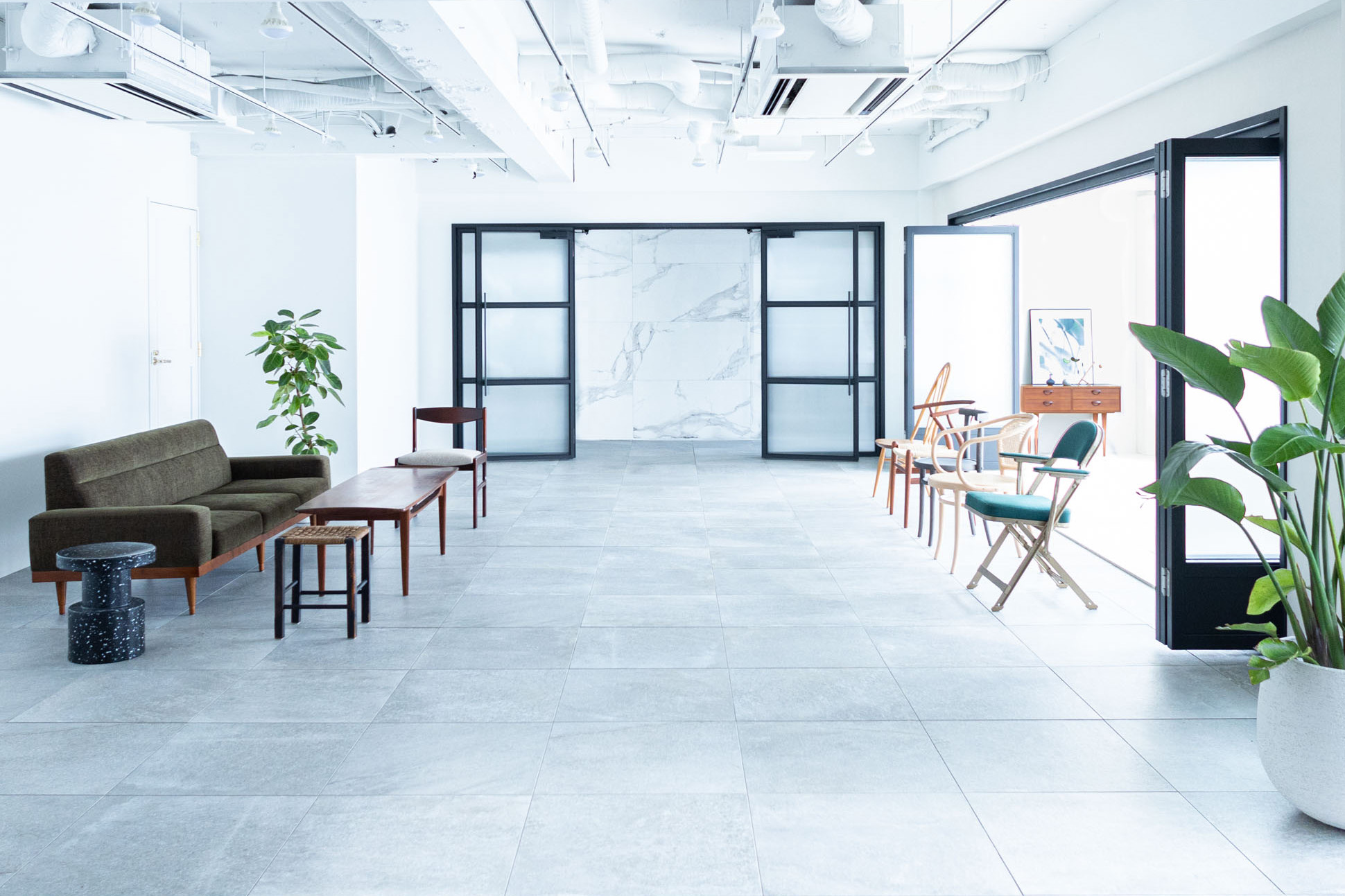 広いタイルの部屋にソファと椅子がならんでいる写真