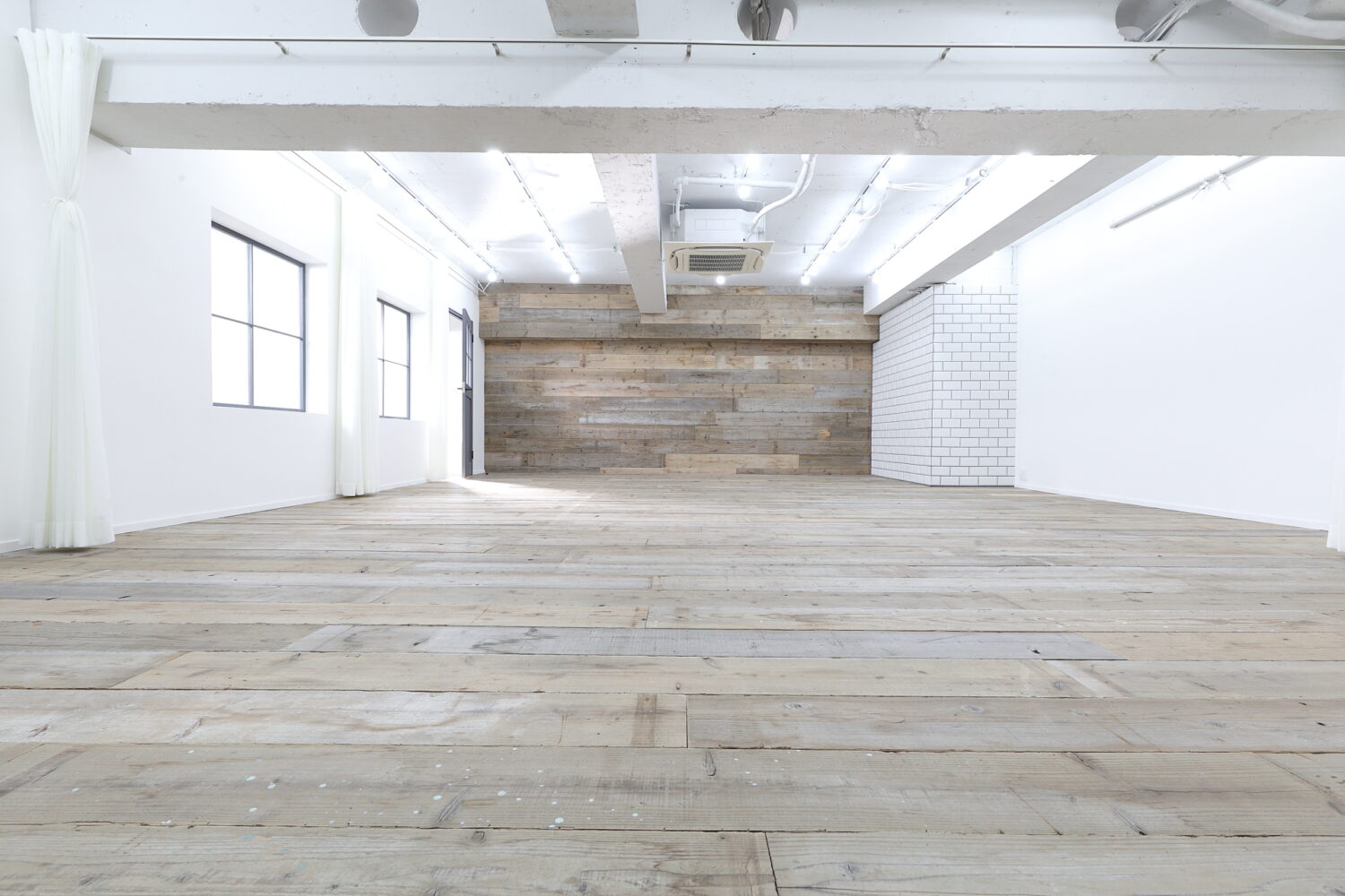 格子窓から柔らかい自然光が入る、ウッドフロアの広い空間