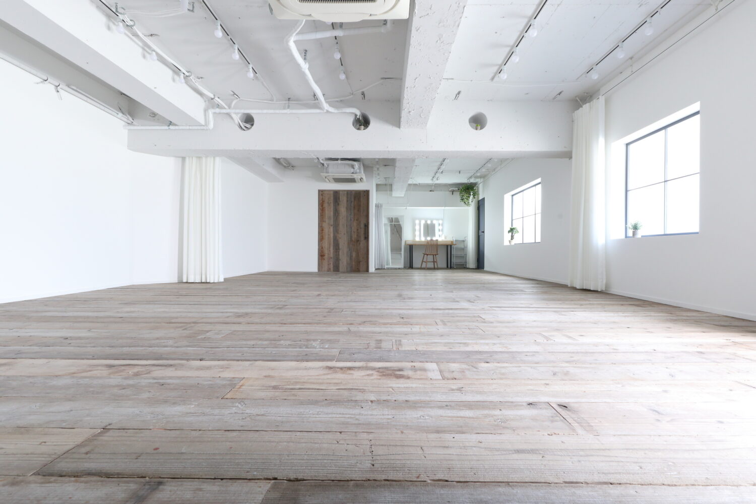 格子窓から柔らかい自然光が入る、ウッドフロアの広い空間