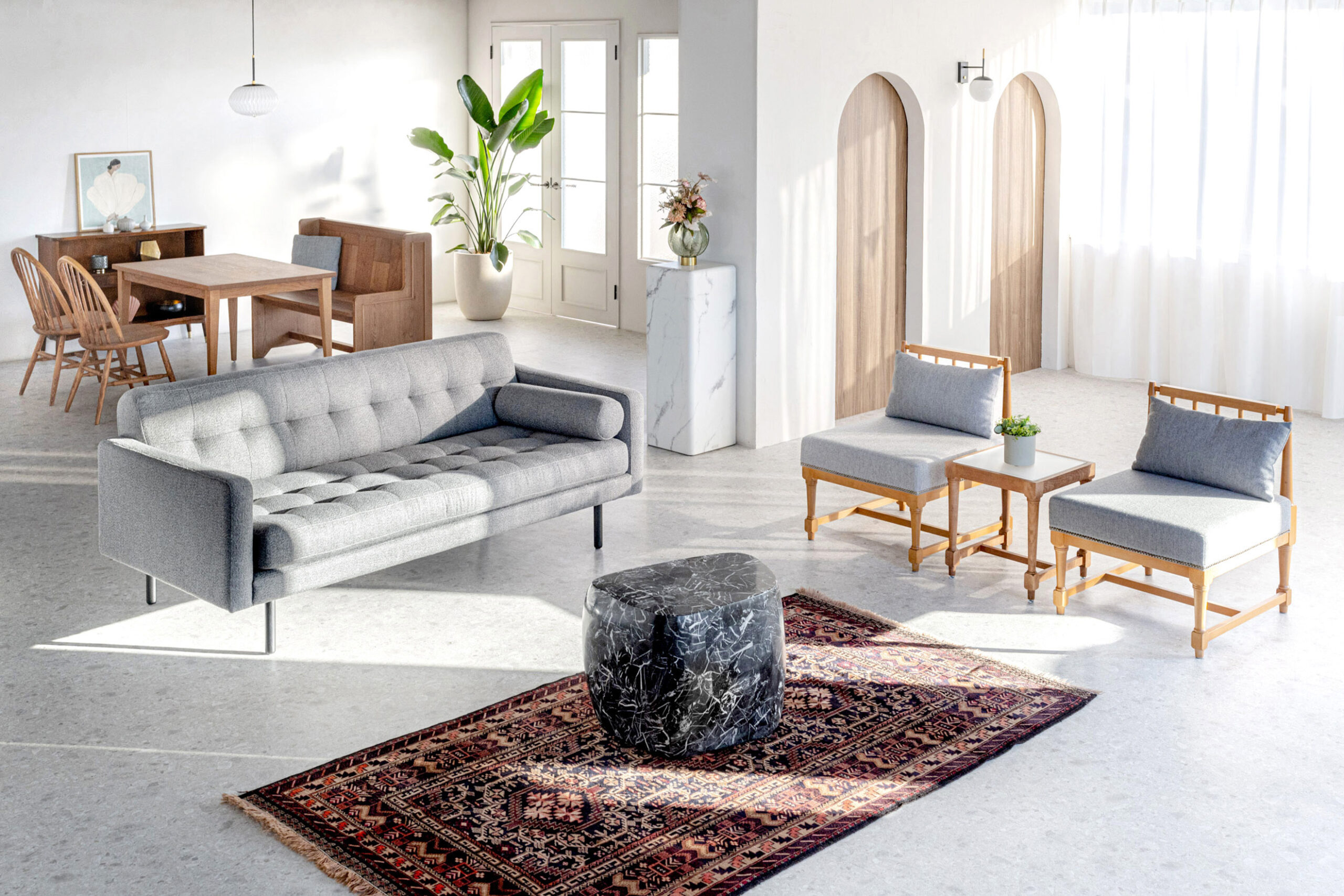 自然光が入るスタジオに、ソファ・椅子・観葉植物などが配置されている写真