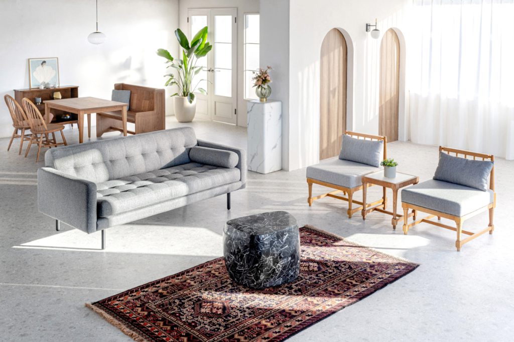 自然光が入るスタジオにソファ、椅子、観葉植物などが配置されている写真