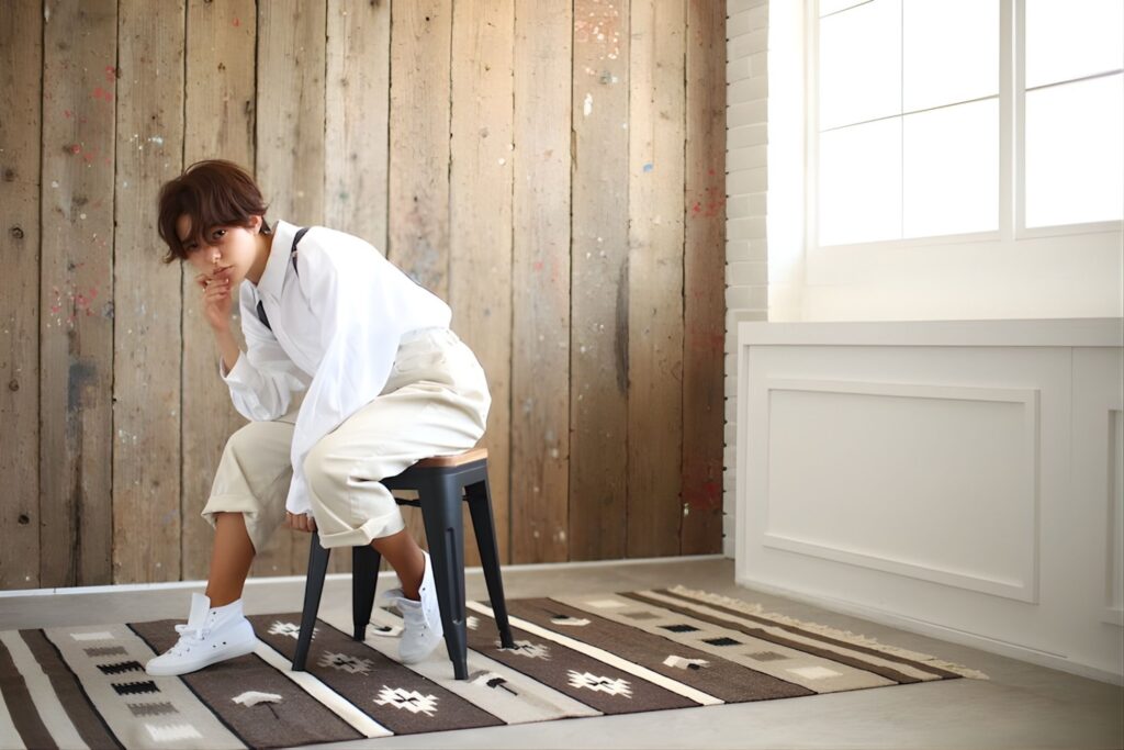 木製壁の前でポーズをとる女性