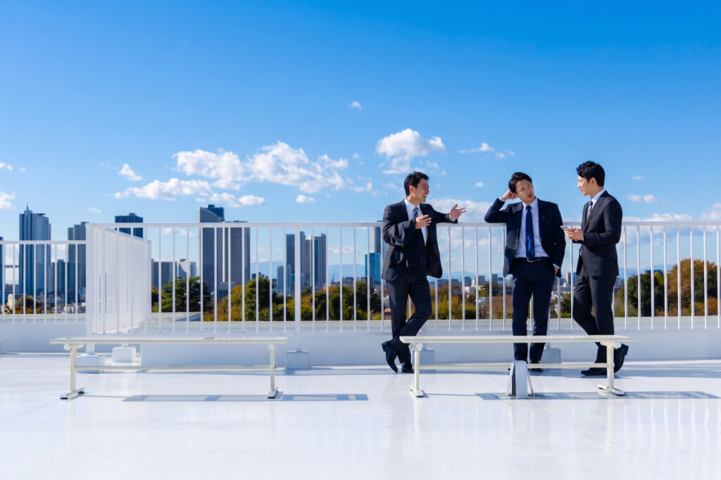 屋上で談笑をしている3名のサラリーマン