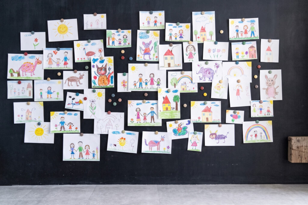 黒板に子どもの絵が沢山貼ってあるシーン